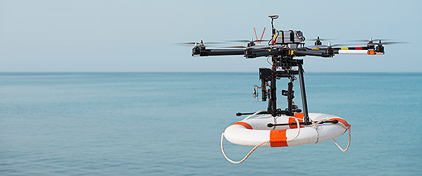 A drone carrying a lifebuoy, flying over water.